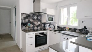 A modern kitchen with white cabinets, a microwave, a coffee maker, and a window providing natural light. - New Downtown House w/ Garden, Parking, WIFI & A/C - 500m to Beach (La Tranche-sur-Mer)