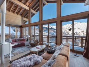 Ein geräumiger Wohnbereich mit einem großen Fenster mit Blick auf eine verschneite Berglandschaft.