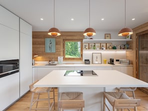 A modern kitchen with a central island, pendant lights, wooden accents, and a view of greenery. - New chalet near slopes, pets allowed (Saint-Martin-de-Belleville)