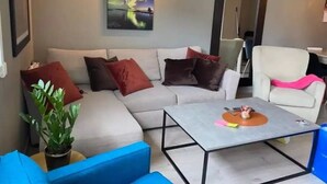 A modern living room with a sectional sofa, a coffee table, and a potted plant.