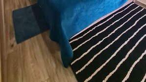 Een slaapkamer met een bed, nachtkastje, spiegel en een plafondlamp.