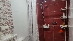 Een badkamer met toilet, douche en betegelde vloer.