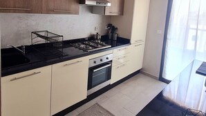 Een moderne keuken met houten kastjes, een gasfornuis, een oven en een zwart aanrecht.