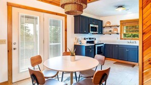 A modern kitchen with dark cabinets, a microwave, and a dining area with a round table and four chairs. - Serene Cabin, Sleeps 12 W Views・Hot tub・Games (Sevierville)