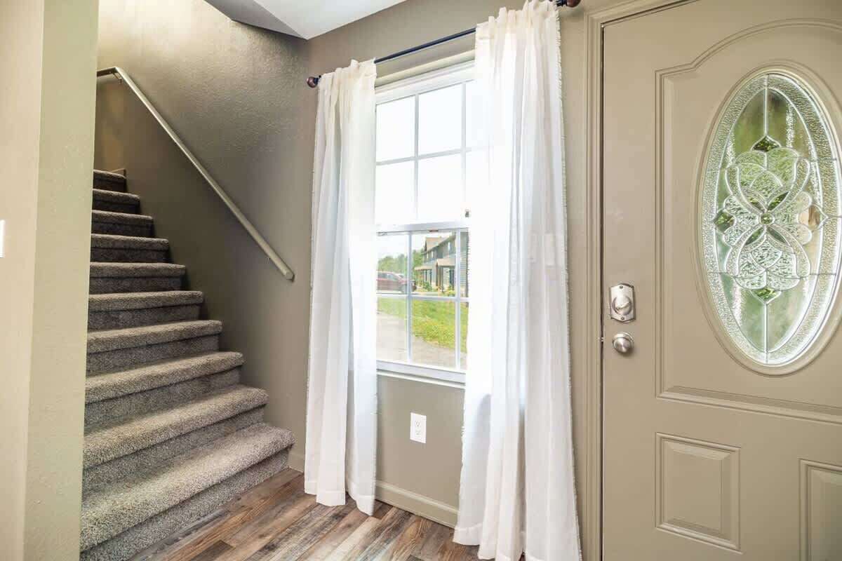 A staircase leading to a landing with a window and a door with a decorative glass panel.