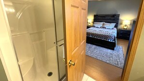 Una camera da letto con un letto, comodini e una porta in legno che conduce al bagno.