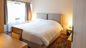 Hotellihuone, jossa on sänky, työpöytä, tuoli, yöpöytä ja lamppu.