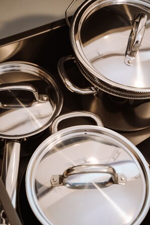 A set of stainless steel pots with lids on a black tray.