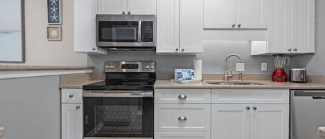 Una cocina moderna con armarios blancos, electrodomésticos de acero inoxidable y encimera de granito.