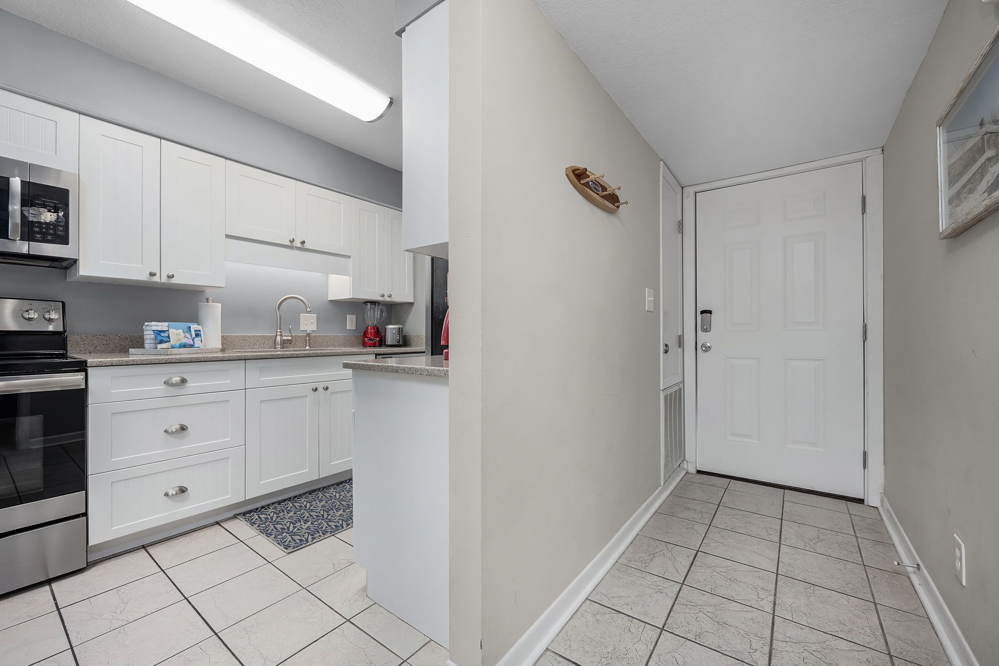 A modern kitchen with white cabinets, a built-in microwave, and a stainless steel oven.