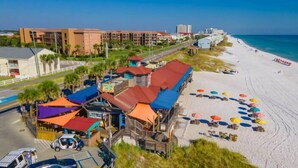 A beachside hotel with multiple buildings, a road, and a beach with umbrellas. - Tradewinds 24 * Across from the beach * Fall Rates * Salt Water Vacations (Miramar Beach)