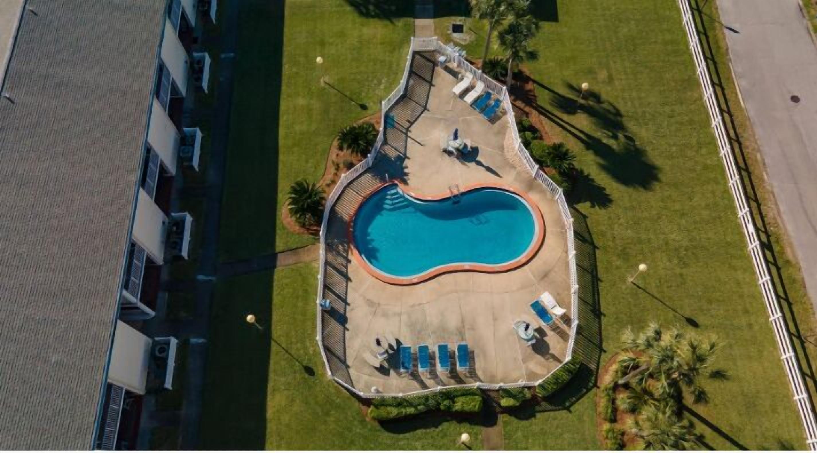Vue aérienne d’une piscine entourée de chaises longues et d’une petite terrasse.