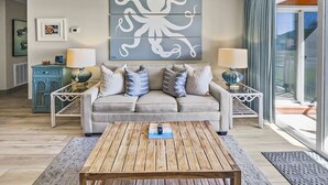 A living room with a sofa, two side tables with lamps, a coffee table, and artwork on the wall. - Tradewinds 26 * Across from the beach * Fall Rates * Salt Water Vacations (Miramar Beach)