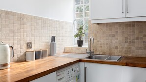 Eine Küche mit einer Holzarbeitsplatte, einem Geschirrspüler von Bosch, einem Spülbecken und einem Fenster mit einer Pflanze.