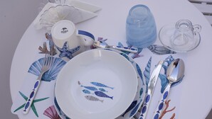 A table set with white plates, blue and red fish patterns, and silverware. - il Truciolo Suite (Anacapri)