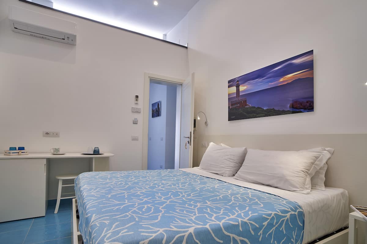 A bedroom with a bed, a desk, and a painting on the wall.