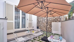 A patio with a table, chairs, and a large umbrella. - il Truciolo Suite (Anacapri)