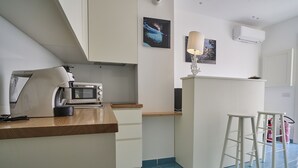 A compact kitchen with a microwave, coffee maker, and bar stools. - il Truciolo Suite (Anacapri)