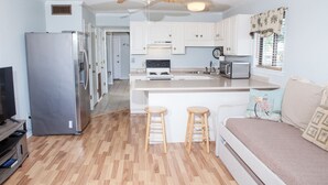 A compact kitchen with a central island, a ceiling fan, and a refrigerator. - Breezy Palms on the Bay!  Dolphins, Pools, Beach (Tybee Island)
