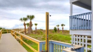 A wooden boardwalk leading to a building with a blue railing and a balcony. - Breezy Palms on the Bay!  Dolphins, Pools, Beach (Tybee Island)
