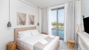 Ein modernes Hotelzimmer mit einem großen Bett, einem Fernseher und Blick auf einen Swimmingpool.