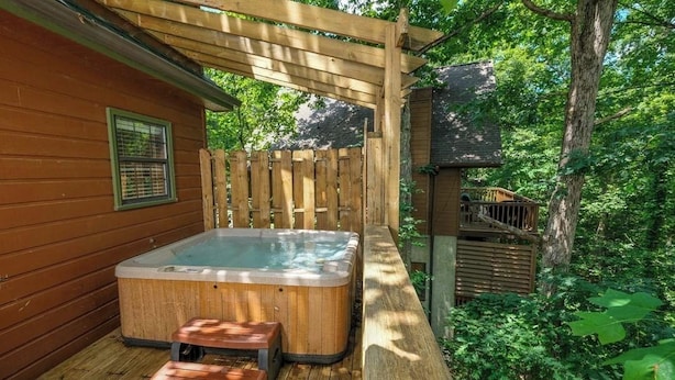 Eine Holzterrasse mit Whirlpool, einer Holzpergola und einem Holzzaun.