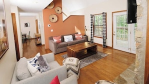 Ein Wohnzimmer mit einer Couch, einem Couchtisch und einem Essbereich im Hintergrund.