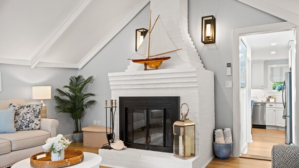 A living room with a fireplace, a sofa, a coffee table, and a potted plant. - Shore Cottage - Coastal gem, a traveler favorite! Outdoor patio, central AC. (Gloucester)