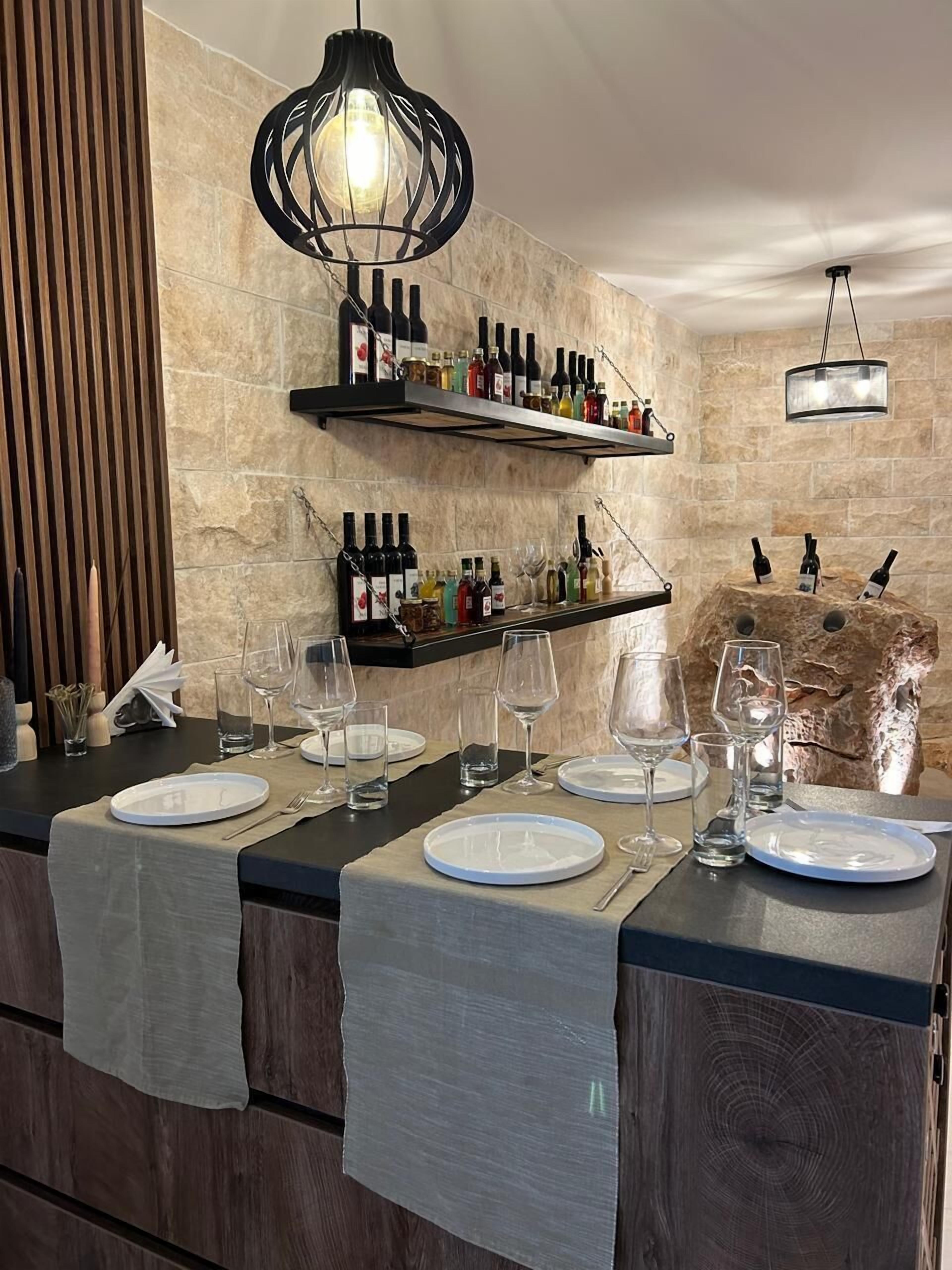 Eine moderne Bar mit einer Steinwand, Weinflaschen in Regalen und einem rustikalen Felsen als Blickfang.