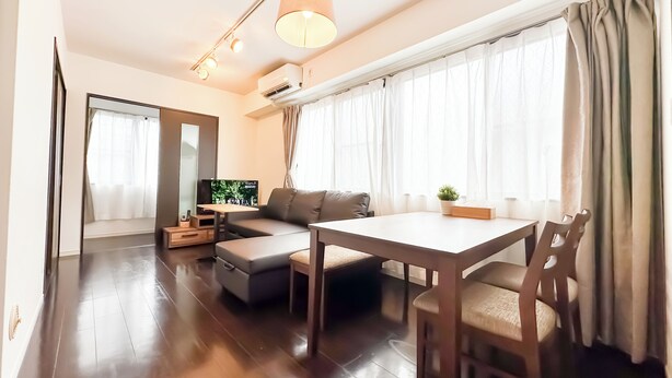 A modern living room with a sofa, a dining table, and a TV. - Near Tsutenkaku, Toy Street, Spacious,Elevator,Wi-Fi,Self check-in, Easy Transit (Osaka)