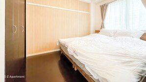 A bedroom with a bed, wooden wardrobe, and a window with curtains. - Near Tsutenkaku, Toy Street, Spacious,Elevator,Wi-Fi,Self check-in, Easy Transit (Osaka)