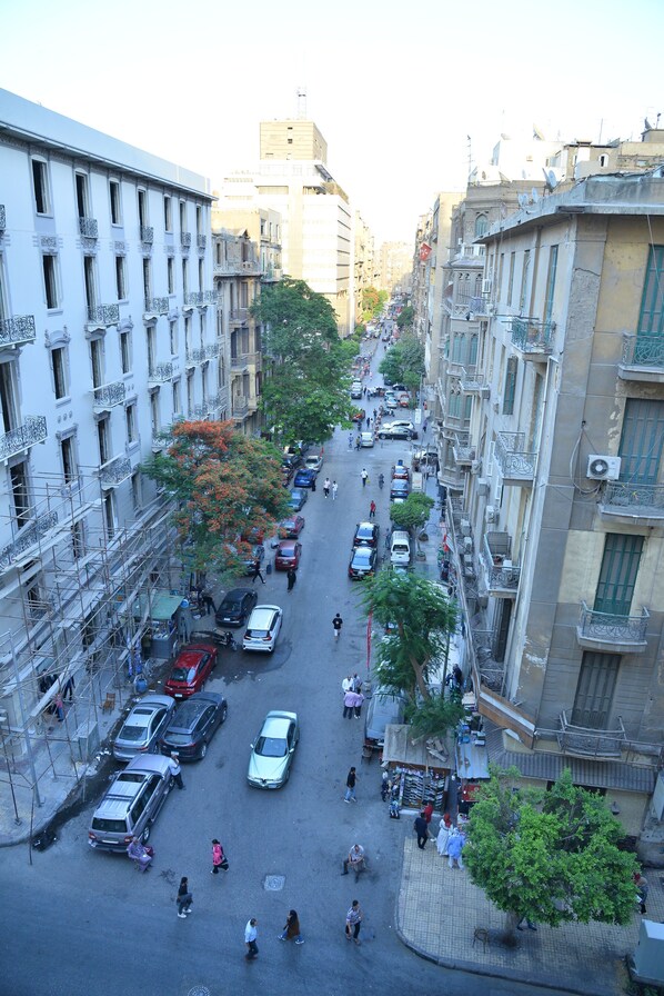 A busy urban street with buildings on either side, vehicles, and pedestrians. - Miramar Evergreen Hotel (Cairo)