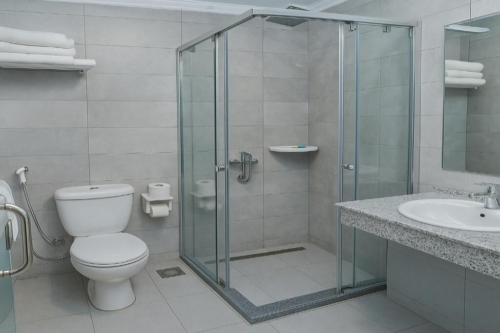 Un baño moderno con ducha de vidrio, lavamanos blanco y retrete.