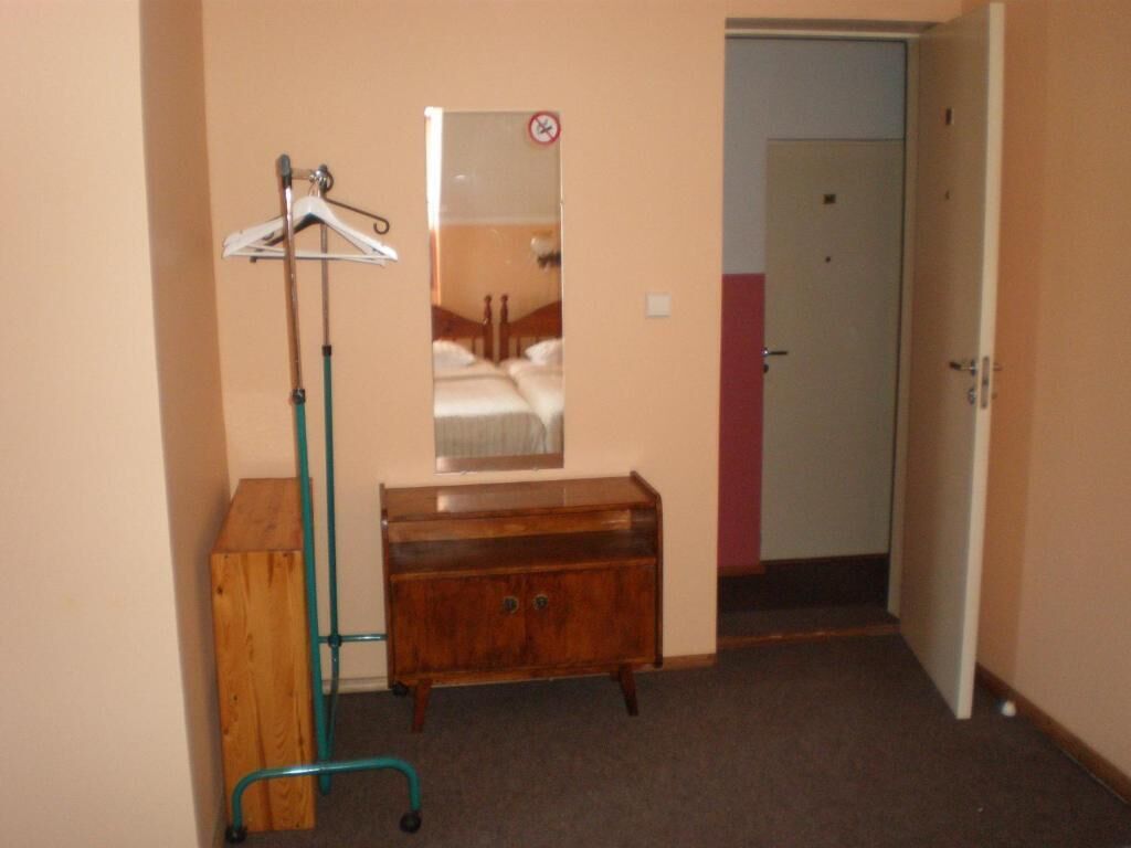 Una habitació amb un armari de fusta, un mirall i una perxa.