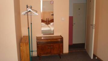 Una habitació amb un armari de fusta, un mirall i una perxa.