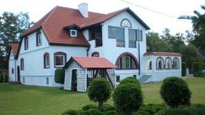 A large white building with a red roof, multiple windows, and a small attached structure with a red roof. - Hotel Getliin (Saku)