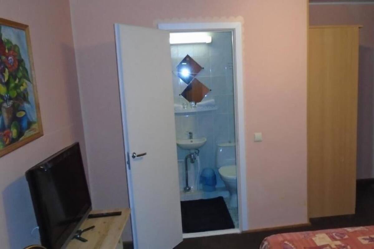 Une chambre d’hôtel comprenant un lit, un bureau avec un ordinateur, une salle de bain avec un lavabo et des toilettes, et une porte donnant sur une autre pièce.