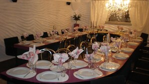 A formal dining room with a long table set for a meal, featuring white plates, silverware, and floral centerpieces. - Hotel Getliin (Saku)