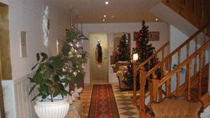 A cozy living room with a checkered floor, a wooden staircase, and a Christmas tree. - Hotel Getliin (Saku)