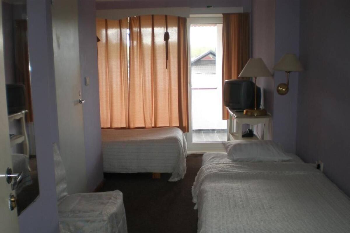 Une chambre d’hôtel avec deux lits, une télévision et une fenêtre avec des rideaux.