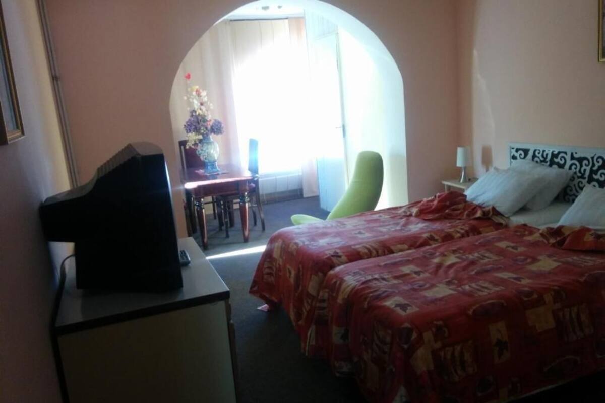 Une chambre d’hôtel avec un lit, un bureau avec une télévision, une chaise et une vue sur l’extérieur.