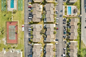 An aerial view of a residential area with multiple parking spaces, a tennis court, and a swimming pool. - Go With The Flow! Pool Just Steps Away! (Panama City Beach)