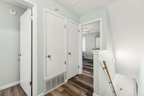 Ein Flur mit weißen Türen, Holzboden und Deckenventilator.