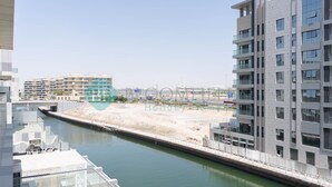 Ein modernes Gebäude mit einem Wasserkanal davor, mit Glasfassade und flachem Dach.