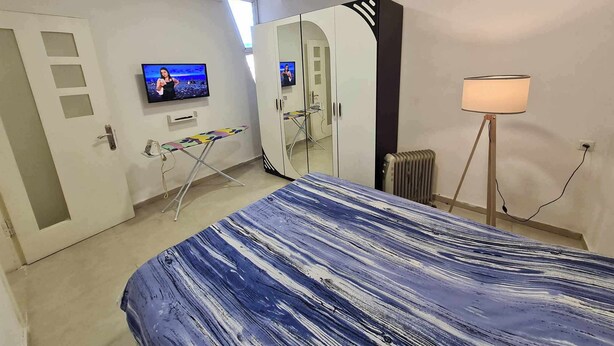 A bedroom with a bed, a TV, a mirror, and a radiator. - 5 minutes walk from sea family apartment (Batumi)