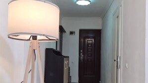A hallway with a floor lamp, a dark-colored cabinet, and a door at the end. - 5 minutes walk from sea family apartment (Batumi)