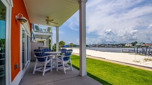 A covered patio with a table and chairs, overlooking a beach and a marina. - Coastal Living Perfected: Banana Bay's Intracoastal Retreat with Sandy Shores (Pensacola)