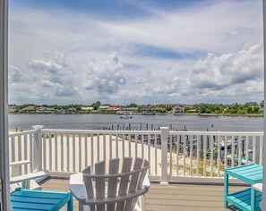 Enjoy serene views of the lake from this balcony, featuring a comfortable Adirondack chair and a small table.