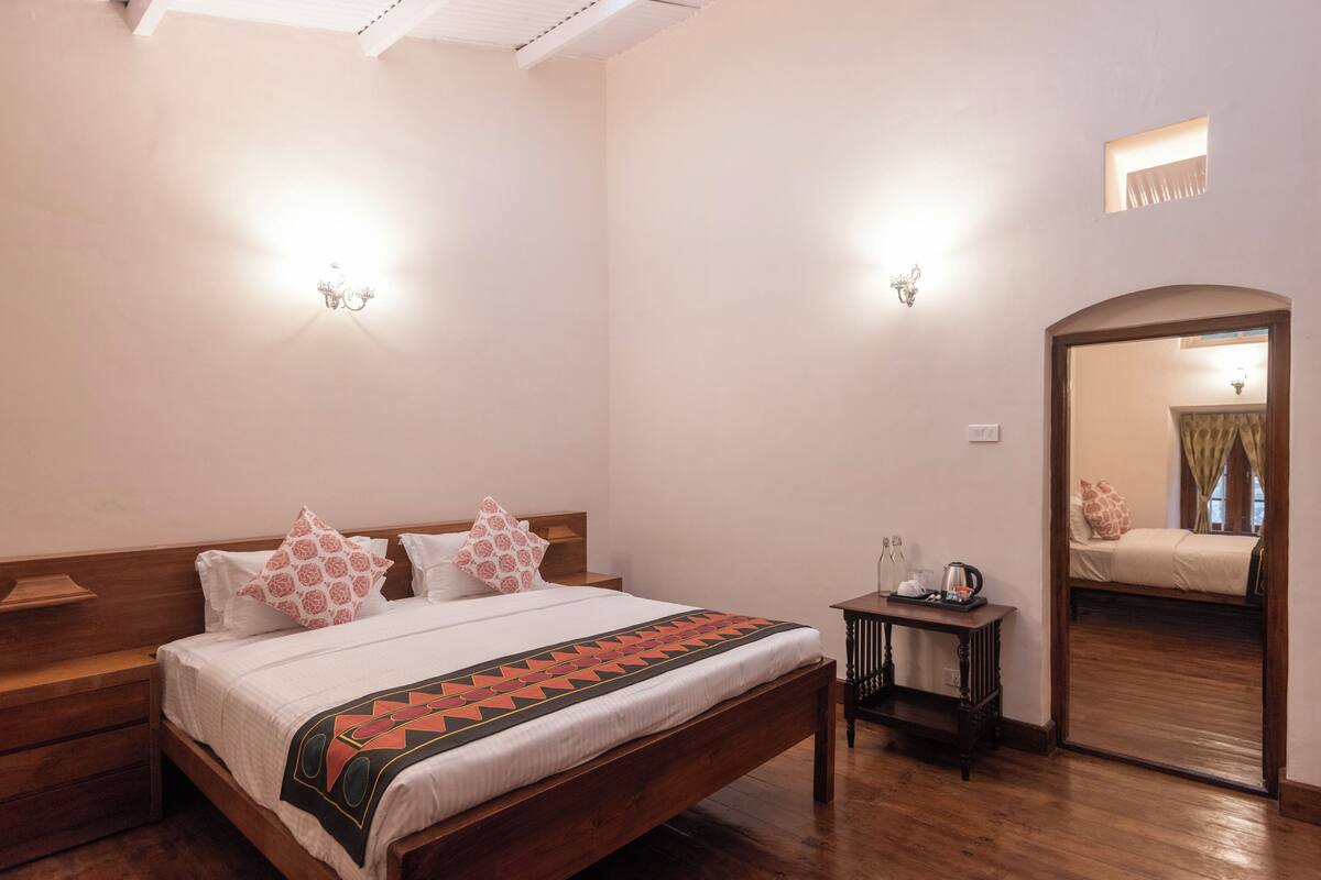 A bedroom with a wooden bed, bedside tables, a nightstand, and a mirror.