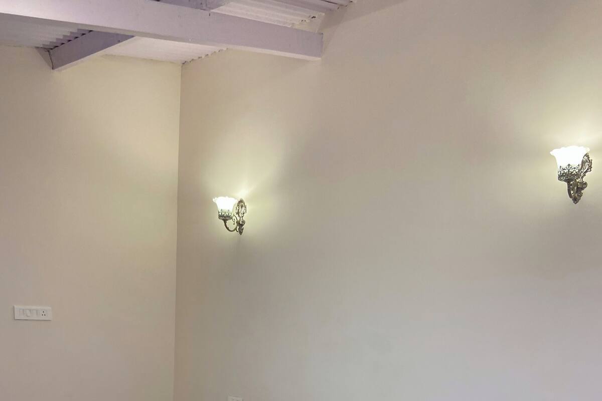 A neatly made bed with a patterned bedspread, two bedside tables with lamps, and a wall-mounted light fixture.